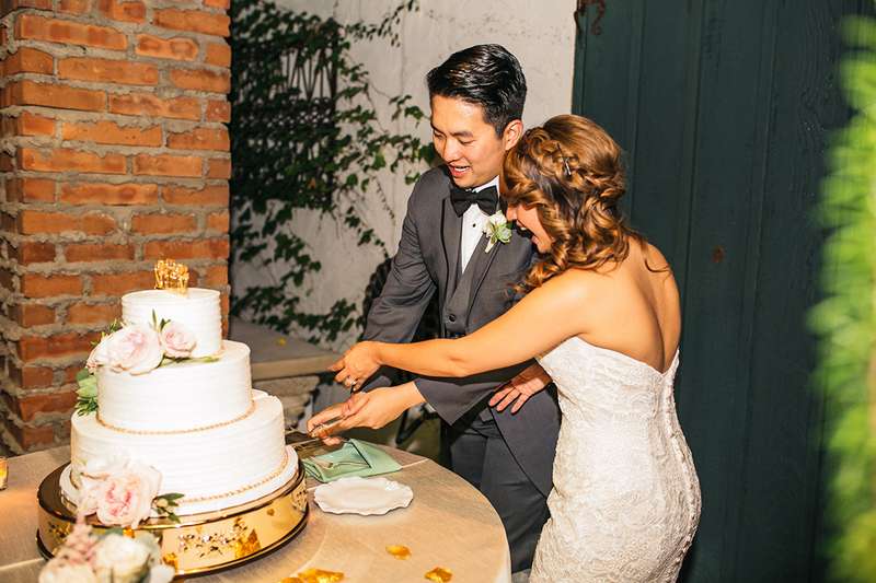 Cutting the cake on your wedding day. Simple white wedding cake with real flower decoration
